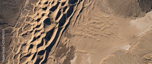 Panoramic aerial texture of wavy sand dunes bordering a flat arid plain with generous copy space