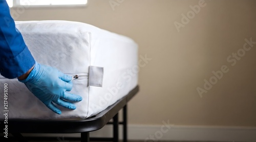 Technician secures a zippered mattress encasement around a bed, showing bed bug prevention, protective bedding and routine pest-control preparation.