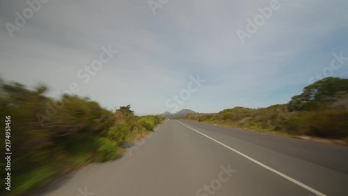 Scenic open road crosses low scrubland near Cape Town, South Africa, with distant hills beneath soft daylight, evoking freedom and travel through wild scenery and open horizons.