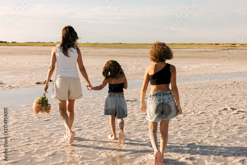 family walking across salt lake holding hands from behind, sunny summer day natural landscape with crystalline shore, family travel childhood adventure tourism promotion destination marketing