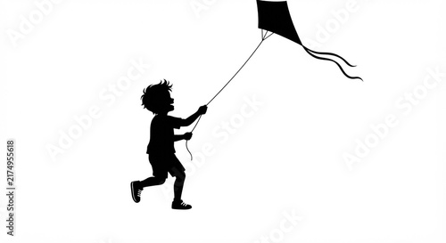 Black silhouette of a young boy happily running and flying a kite