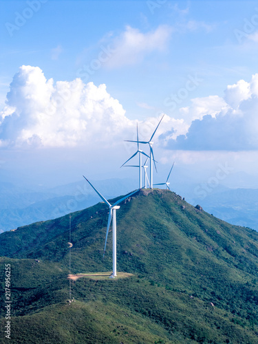 Aerial view of mountain wind farm under bright blue sky, renewable energy