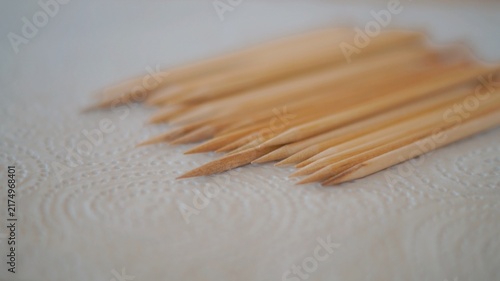 Several pointed wooden manicure sticks are neatly arranged on an embossed white paper towel. The image represents nail-care preparation, cleanliness, precision, and hygienic personal grooming.