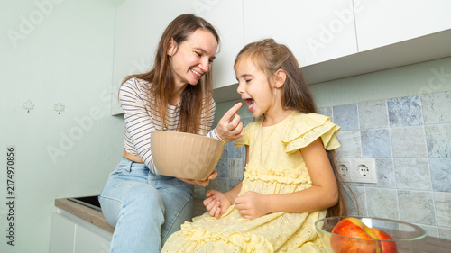Happy day! Mom and her daughter child girl are playing, smiling, eating fruit in the kitchen. Family holiday and togetherness.