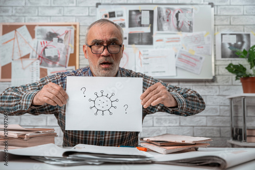 Konstfotografi Suspicious older man presenting a homemade virus diagram while questioning infor
