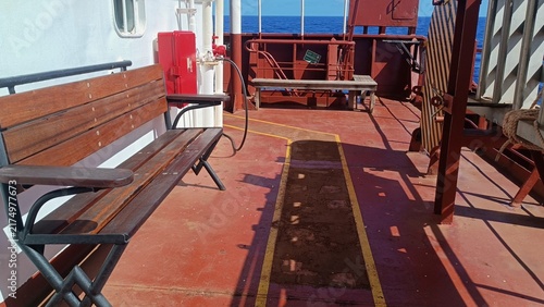 Foto Benches and equipment are arranged on an open cargo ship deck beneath bright daylight at sea