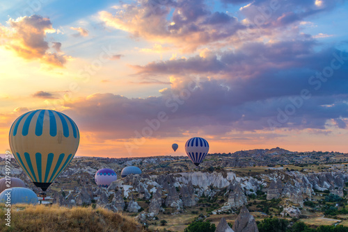 Hot air balloons flying over rocky valley at sunset. Hot air ballooning represents freedom exploration dream.