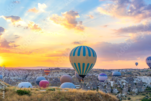 Hot air balloons flying over rocky valley at sunset. Hot air ballooning represents freedom exploration dream.