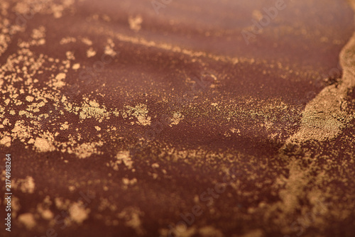 Artistic background featuring reddish-brown swirls with gold accents; photo of the surface.