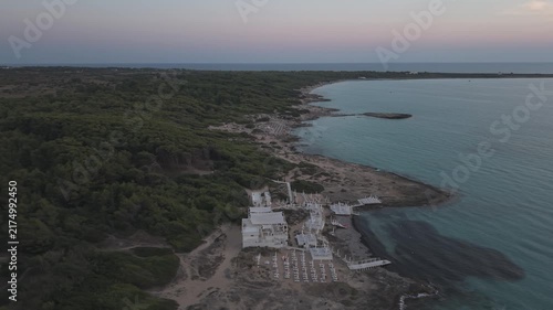 Aerial drone perspective of Punta della Suina beach resort and coastline in Gallipoli, Puglia. Crystal clear turquoise water and Mediterranean scrub at sunset.