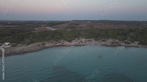 Aerial drone perspective of Punta della Suina beach resort and coastline in Gallipoli, Puglia. Crystal clear turquoise water and Mediterranean scrub at sunset.