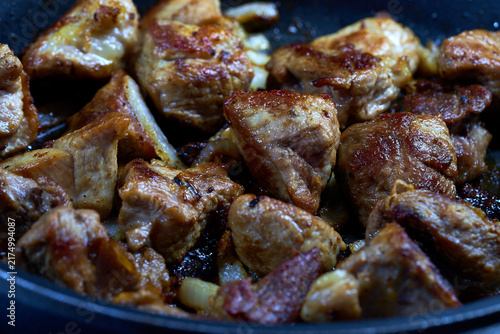 Fried pork pieces in a frying pan. Selective focus.