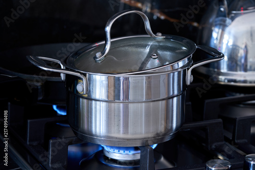stainless steel pot on gas stove in kitchen with black background