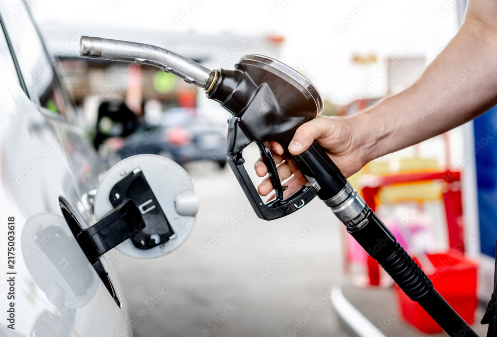 Fototapeta premium Person filling up white car fuel tank at local gas station