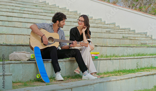 Canvas Print Indian young adult gen z female male man hold guitar play new lyric music sing song have fun joy stairway place