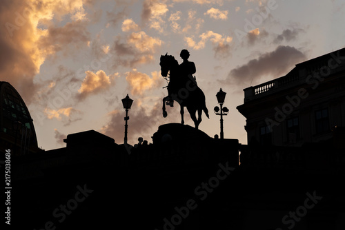 Equestrian statue silhouette against dramatic sunset sky in Vienna Austria