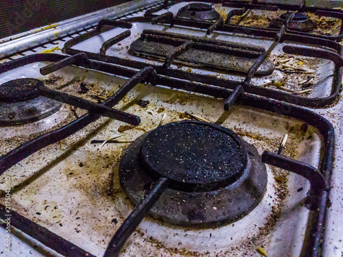 dirty cookers multiple burners, greasy surface, Burnt matchsticks, white enamel coated surface, black burner, glass cover, Enameled cooker, selective focus, shallow depth of field, Cairo Egypt