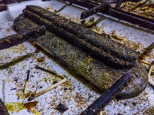 dirty cookers multiple burners, greasy surface, Burnt matchsticks, white enamel coated surface, black burner, glass cover, Enameled cooker, selective focus, shallow depth of field, Cairo Egypt
