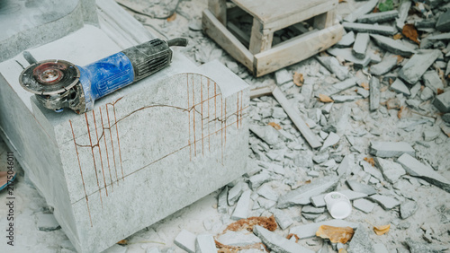 Картината върху платно Power grinder tool on white stone block surrounded by carving debris in sculptor