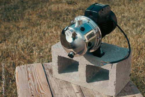 Canvastavla Stainless steel surface water pump mounted on concrete cinder block placed on wo