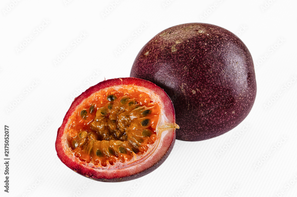 Obraz premium Halved passion fruit with vibrant orange pulp and black seeds on white background