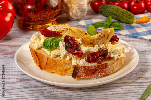 Fotografie Bruschetta with ricotta cheese, sun dried tomatoes, artichoke hearts and basil o