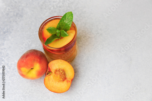 Obraz na plátně Fresh peach iced tea served with peach slices and mint leaves in a glass on a gr