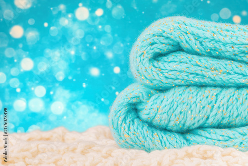 Blue knitted scarf on light bokeh background with copy space.