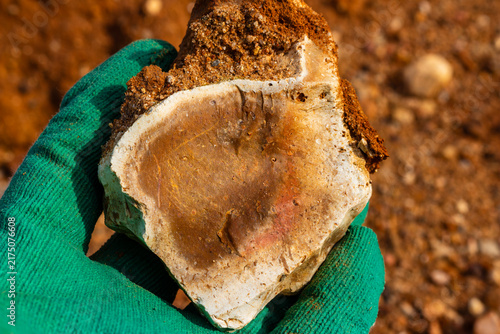 Canvastavla Raw flint stone held in a green gloved hand against a backdrop of a quarry, show