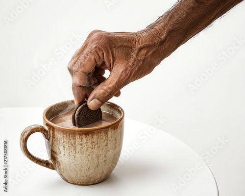 Close-up of an Older Person's Hand Dipping a Chocolate Biscuit into a Mug of Hot Chocolate Beverage
