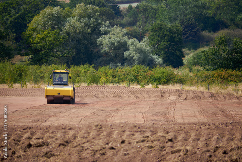 Building on Greenbelt or Brown field site on the edge of the country side. A Yellow construction vehicle in action.