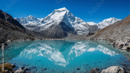Majestic snow-capped mountains reflected in a pristine turquoise glacial lake during daylight with clear blue sky