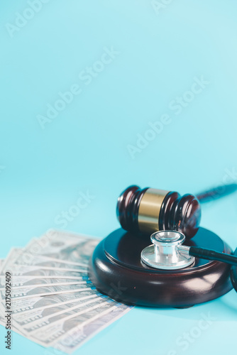 Obraz na płótnie Judge gavel and stethoscope beside US dollar banknotes on blue represent medical