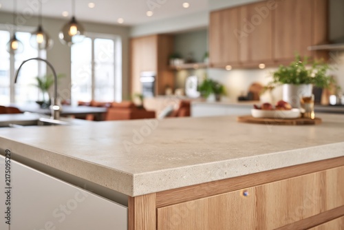 Counter height close-up across a seamless pale concrete kitchen worktop occupying most of the foreground, subtle mineral texture and softly rounded edge rendered sharply while handleless timber