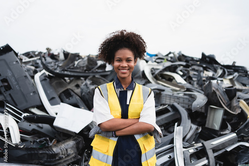 A recycling worker lifts a recovered automotive component at a scrapyard, illustrating manual work, material recovery, and sustainable vehicle recycling