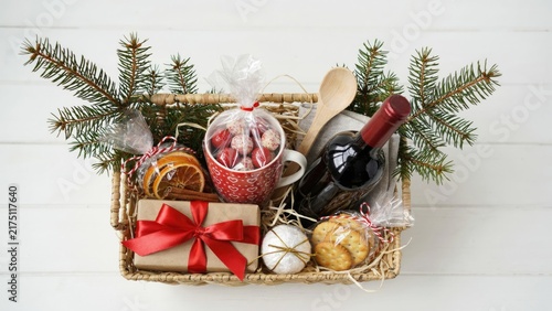Christmas gift basket with wine, red mug, cookies, and pine branches