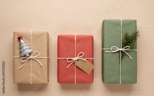 Three wrapped christmas gift boxes with decorations on beige background