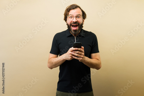 Foto Holding a smartphone, a man discovers unexpected content, reacting with shocked