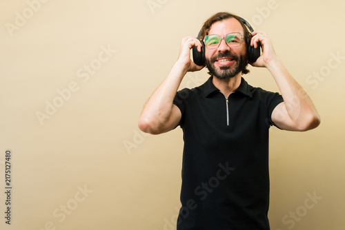 Konstfotografi Cheerful man enjoying favorite music, smiling, adjusting black headphones, findi