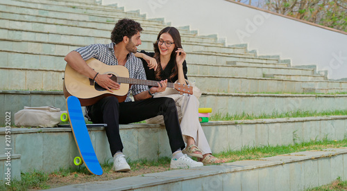 Foto Indian young adult gen z female male man hold guitar play new lyric music sing song have fun joy stairway place