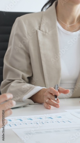 Business team analyzing financial data and discussing marketing strategy during a meeting in the office, businesswoman pointing at charts and explaining strategy to colleagues