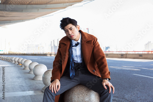 Obraz na płótnie Frustrated young businessman sitting by urban roadside looking stressed