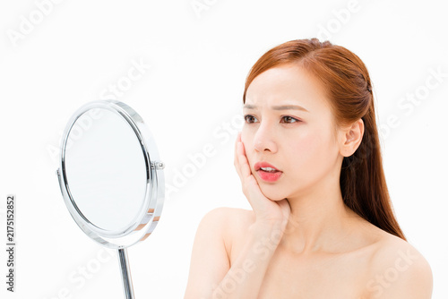 Obraz na płótnie Worried woman touching cheek while looking in mirror