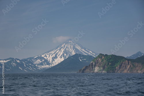 Cuadro en lienzo Snow-covered Vilyuchinsky Volcano rises beyond green coastal cliffs and Pacific water in Avacha Bay, Kamchatka, Russia