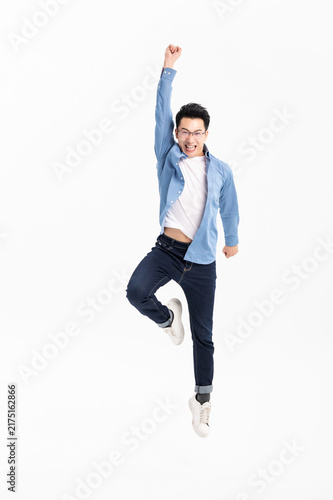 Excited young man jumping with raised fist in casual outfit