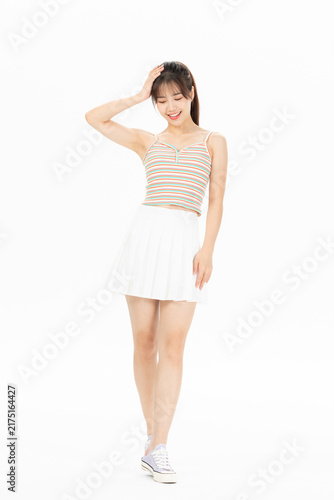 Obraz na plátne Smiling young woman in striped camisole and white skirt posing on white backgrou