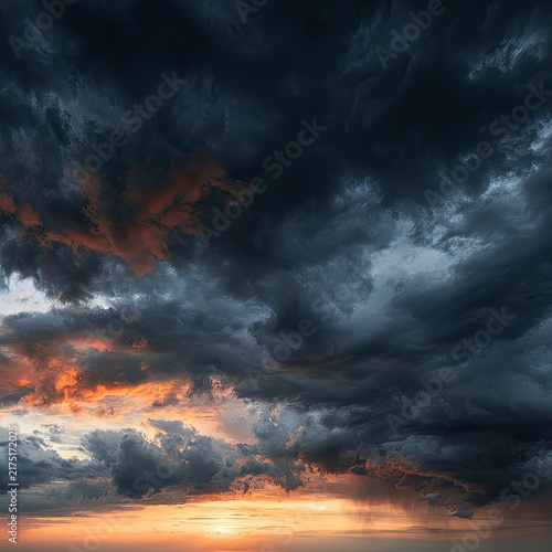 Dramatic sky with fiery sunset peeking through dark, moody clouds