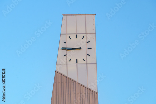Modern minimalist clock tower against a clear blue sky background