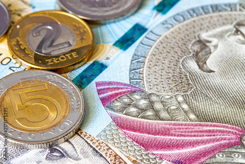 Polish zloty coins rest on top of 200 and 500 zloty banknotes. Polish national currency PLN. European finance.