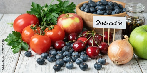 Quercetin rich foods, fresh fruits and vegetables on white wood table